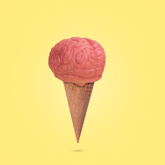 Creative funny  idea made from a waffle cone of ice cream and the human brain on a yellow...