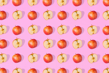 Outstanding pattern of fresh whole apples  and apple halves on a pink  background.
