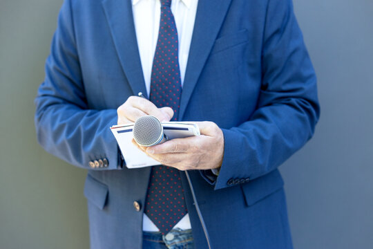 Well-dressed Journalist At News Conference Or Media Event, Holding Microphone, Writing Notes