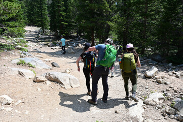 Hikers ascend Saint Mary's Glacier Trail in Arapaho National Forest, Colorado on sunny summer morning.
