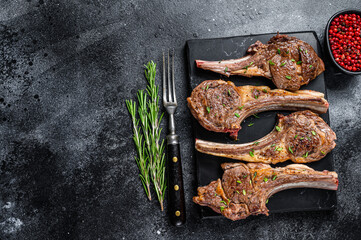 Barbecue fried lamb meat chops on a marble board. Black background. Top view. Copy space