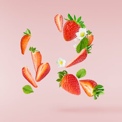 Fresh raw ripe strawberry with green leaves falling in the air, food levitation