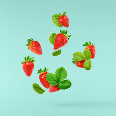 Fresh raw ripe strawberry with green leaves falling in the air, food levitation