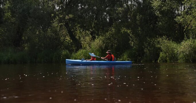Kayaking on the River. Boy and man tourists kayaking down the river, teamwork