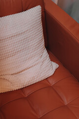 Fototapeta na wymiar Details of a cozy home interior in autumn shades. Orange armchair and white pillow