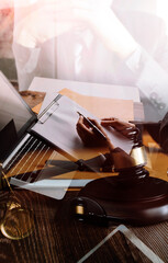 Justice and law concept.Male judge in a courtroom with the gavel, working with, computer and docking keyboard, eyeglasses, on table in morning light
