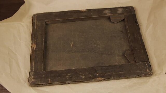 The reverse side of the canvas on the subframe. Paper unfolds and an ancient painting is found in it.