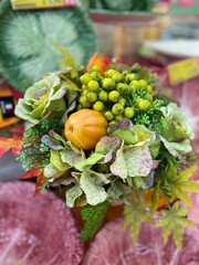 Autumn decorative composition of artificial vegetables and leaves in green tones with an orange accent.