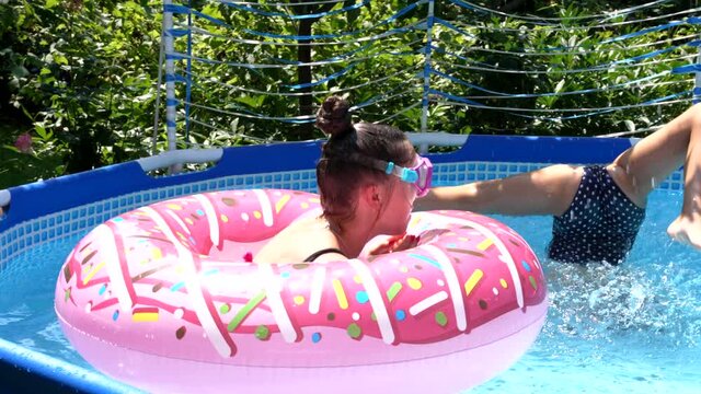 Children in swimming masks dive in outdoor pool on sunny summer day, diving