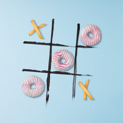 Donuts and french fries to play tic tac toe. - obrazy, fototapety, plakaty