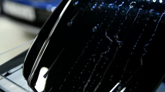 Video showing advantages of using ceramic coating on mini car hood. Hydrophobic effect on water pouring on metal surface