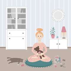 The girl is at home. A woman sits in a lotus position and is engaged in a hobby, sews a handmade soft toy bear. 