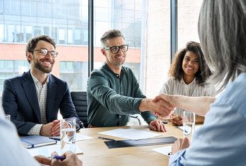 Happy businessman and businesswoman shaking hands at group board meeting. Professional business executive leaders making handshake agreement successful company trade partnership handshake concept. - obrazy, fototapety, plakaty