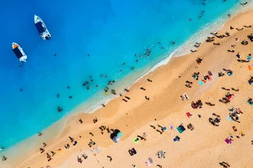 Cercles muraux Plage de Navagio, Zakynthos, Grèce Aerial view of Navagio beach, Zakynthos Island, Greece. People relaxing on the beach during their vacation. Blue sea water. A boat drops people off at the seashore. Summer landscape from drone.