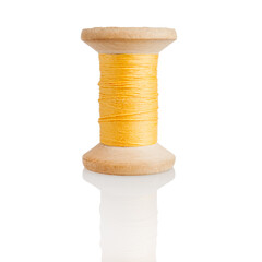Wooden spool with yellow threads, embroidery and sewing, tailor isolated on a white background,...