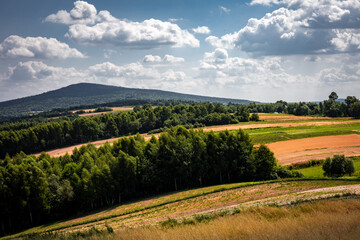 Fototapeta na wymiar A picturesque countryside panorama of hilly, golden fields, green forest and Lysica Mountain. Swietokrzyskie Mountains, Poland.