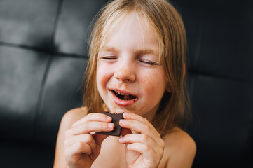 A portrait of the face of a little red-haired girl, a child, who is smeared with milk chocolate and...