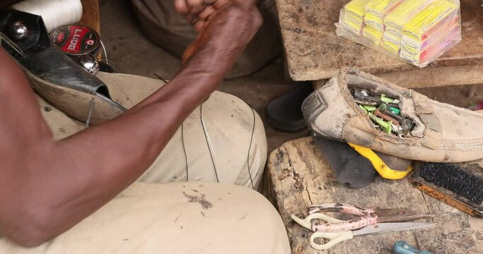 Old Man Shoe maker cobbler repair sandal Accra Ghana. Old Muslim shoe maker and cobbler. Poverty section of Accra Ghana. Happy to repair people shoes for very little income.