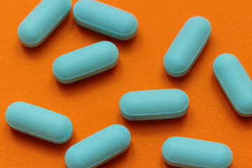 scattered blue pills on a contrasting bright orange background