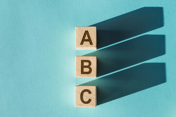 Wooden cubes building word ABC on light blue background.