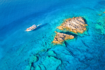 Fototapeta na wymiar Aerial view of beautiful yacht on the sea and rocks at sunny day in summer in Turkey. Top view of boat, stones, clear blue water. Tropical landscape. Travel. Nature background. View from above. Cruise