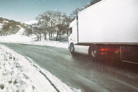 White modern truck moving fast in winter on a road with snow