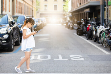 Asian Child is watching the phone on the road crossing or using a mobile phone for a long time hurts her eyes and has an aggressive atmosphere. Concept danger for children's mobile phones.