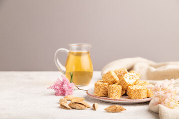 Traditional turkish delight (rahat lokum) with glass of green tea on a gray concrete background, side view, copy space.