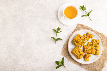 Traditional iranian dessert sohan with cup of green tea on a gray concrete background, top view, copy space.