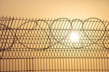 Barbed wire against the setting sun. Metaphor of slavery and the search for freedom