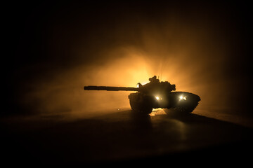 War Concept. Armored vehicle silhouette fighting scene on war foggy sky background at night....