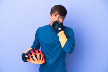 Young cyclist caucasian man isolated on purple background happy and smiling covering mouth with hand - obrazy, fototapety, plakaty