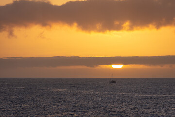 Fototapeta premium sunset over the sea with a boat at the horizon