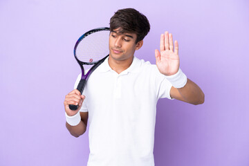Handsome young tennis player man isolated on ocher background making stop gesture and disappointed