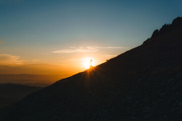 silhouette of man climbing mountain at sunset with magical sunset. effort, achievements