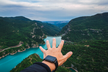 hand with smart watch and nature landscape in the background