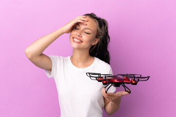 Teenager Russian girl holding a drone isolated on purple background smiling a lot