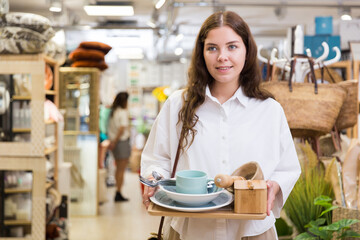 Positive young female customer looking for tableware in home decor store