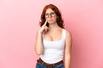 Teenager reddish woman isolated on pink background and thinking