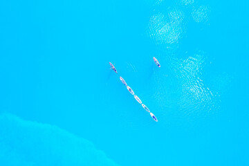 SUP board surfing. Aerial image of people paddling on sup boards and blue water.