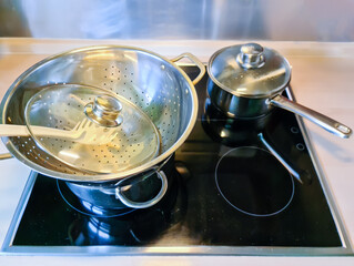 High angle view of a chrome pasta strainer in a pot on a stove.