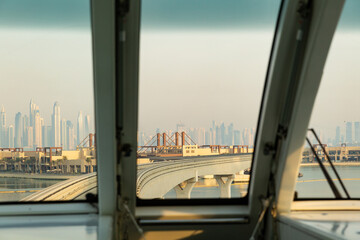 evening cityscape with skyscrapers and ocean seen from inside monorail in dubai, uae