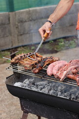 Man cooking pork rib, sausage and grilled beef churrasco on a barbecue.