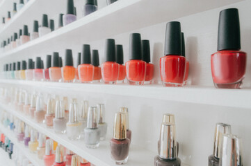 Filas de botellas de esmalte de uñas ordenadas por por tonalidades, multicolor.