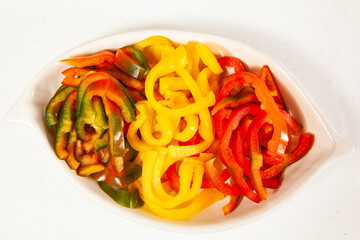 Fish marinade preparation steps: Red, green and yellow pepper cut in julienne strips