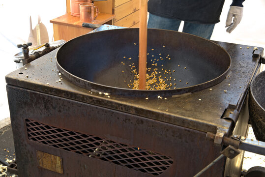 FOOD: Worker stirs kernals of popping corn in a large kettle at an outdoor activity.. Kettle corn