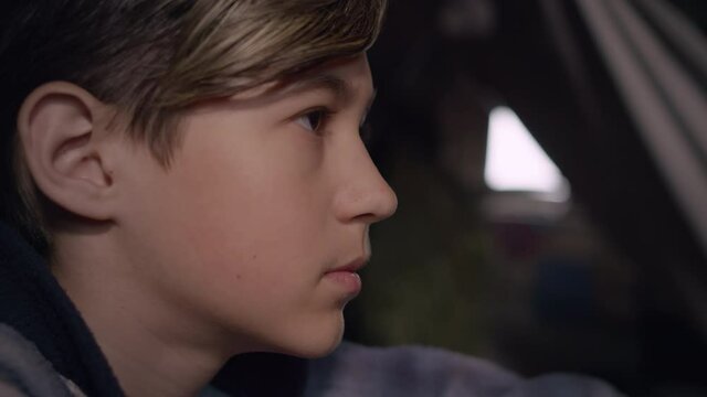 cinematic profile of a serious sad boy looks and thinking about something in an abandoned house, moving camera