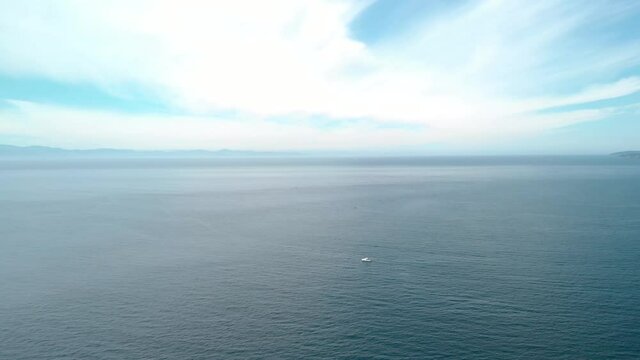A aerial drone shot of boats on the ocean, beautiful clouds and coastline in the distance near Sooke, BC. 4K 24FPS.