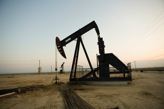 Silhouette of pump jack in oil field at sunset