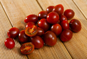 Ripe red cultivated species kumato tomatoes on wooden background. Healthy vitamin product